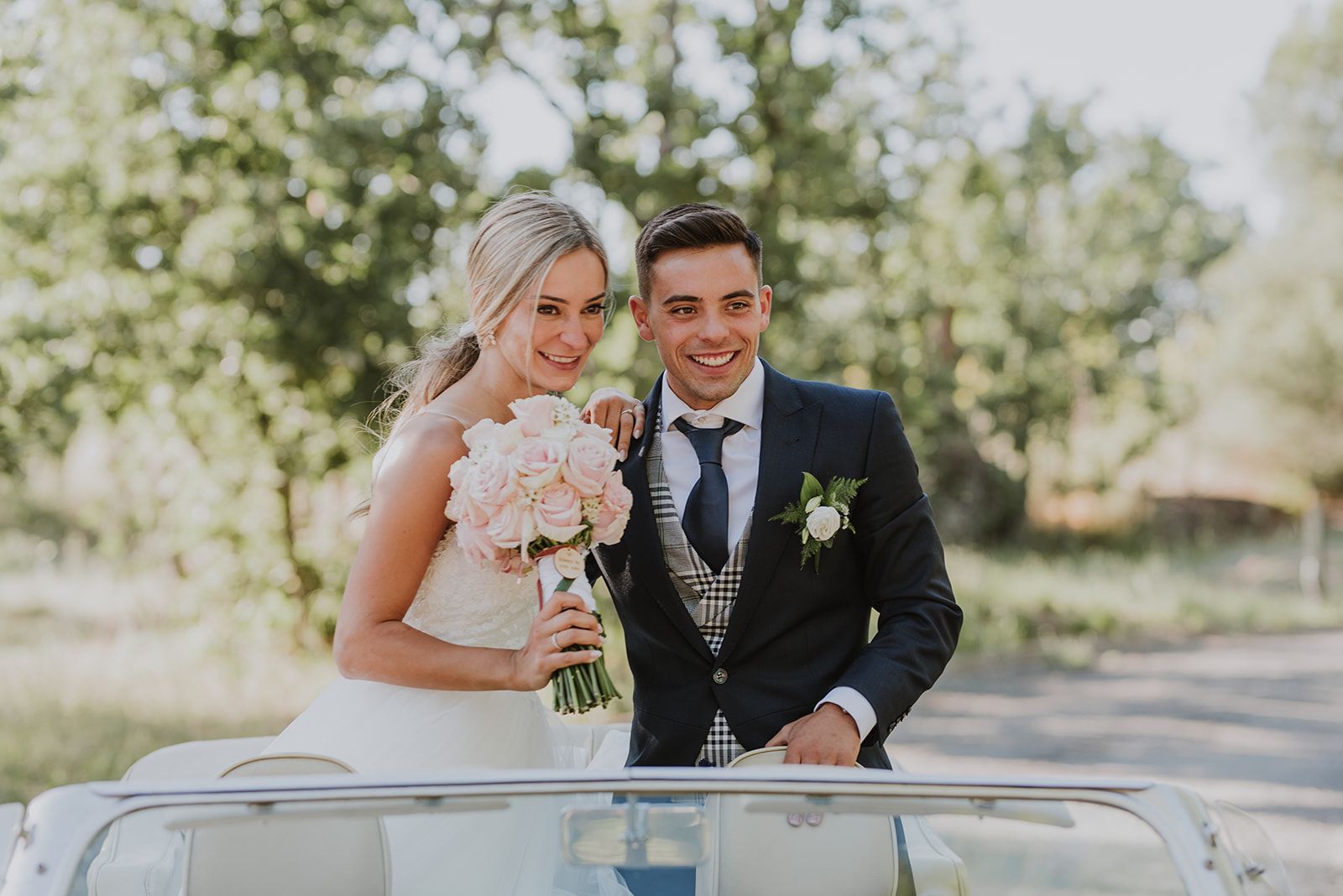 Novios saludando desde un coche descapotable el día de su boda
