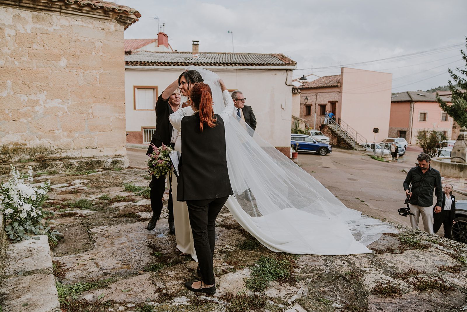 Organizadora de bodas colocando el velo a la novia a la salida de la iglesia