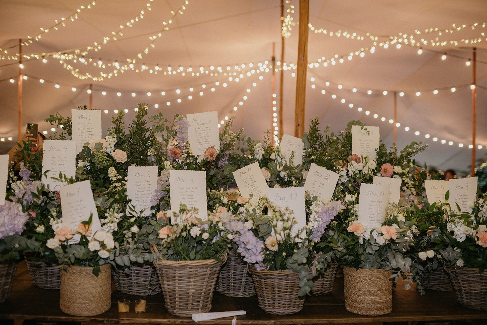 Seating plan de boda con las listas de mesas entre cestas de flores